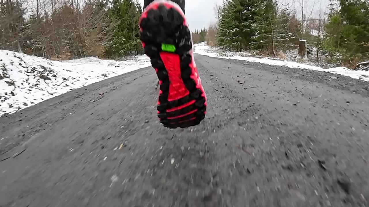 Close up rear view slow motion of a trail runner on wintery forest trails