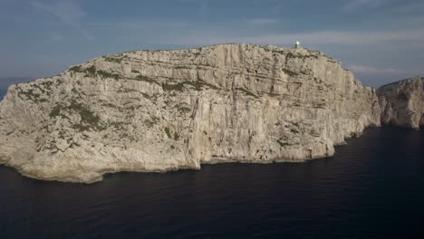 aerial orbit over the cliffs of capo coccia with a small lighthouse on the top, sardinia, italy