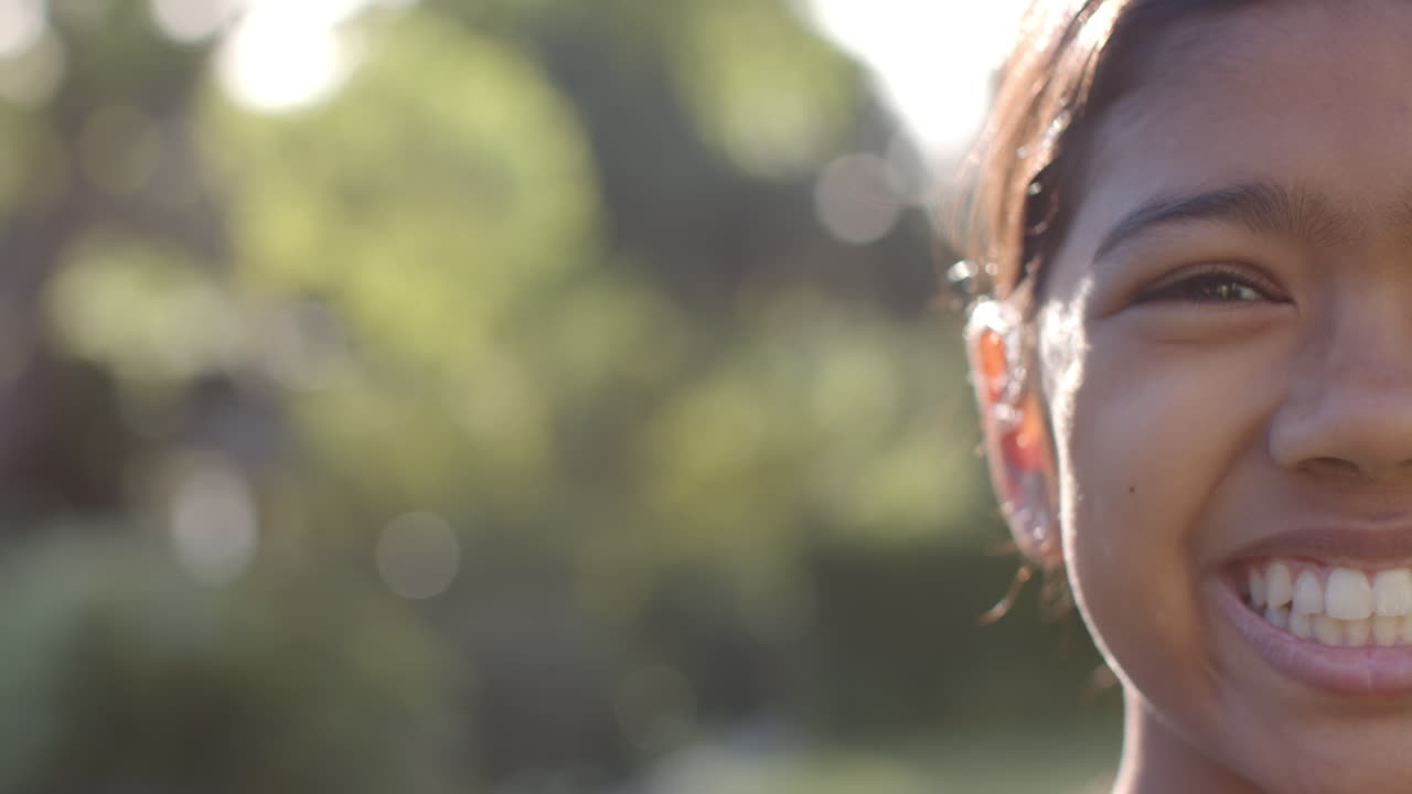 Smiling girl outdoors enjoying sunny day, close-up of face with blurred background, copy space