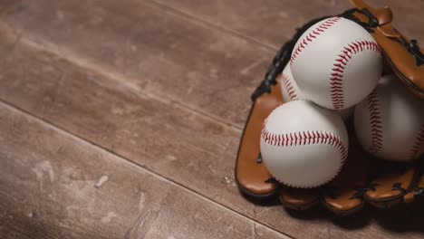 Cerrar-Estudio-De-Béisbol-Bodegón-Con-Pelota-En-Guante-De-Receptor-En-El-Suelo-De-Madera