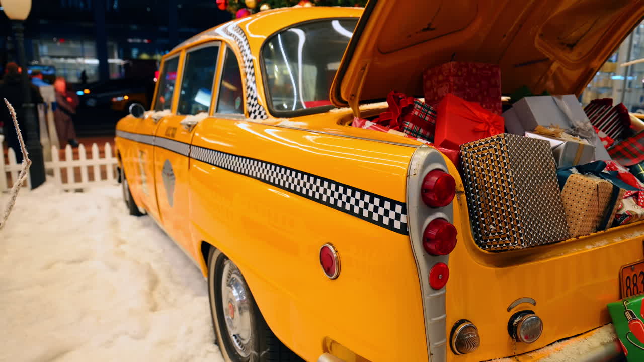 New York, USA, 5. Dezember 2025: Gelbes Oldtimer-Taxi mit Weihnachtsgeschenken im Kofferraum. Ein gelbes Checker-Taxi mit einem offenen Kofferraum voller gemusterter Weihnachtsgeschenke wird in einer verschneiten Feiertagsumgebung präsentiert.