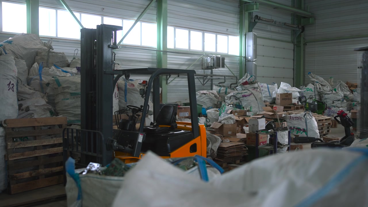 Forklift Behind Giant Sacks In Shed With Bulging Bags And Stacked Pallets In Foreground Diffuse High Window