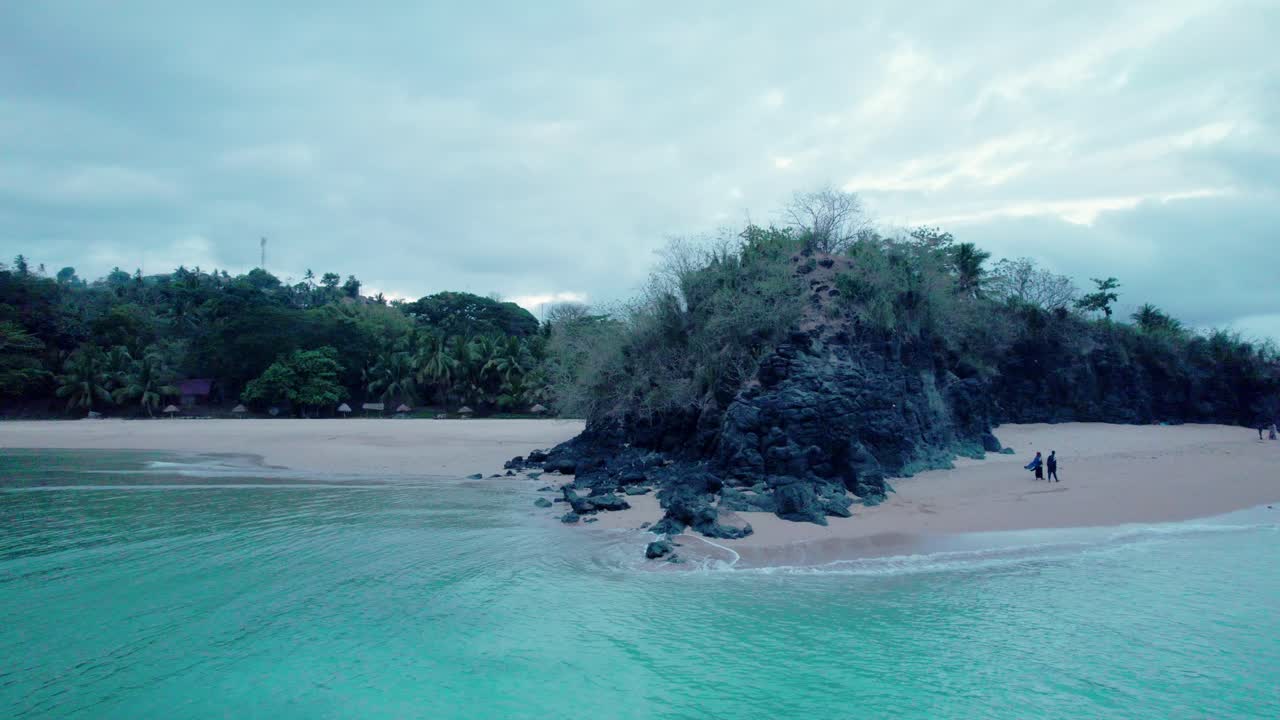 어두운 흐린 날에 해변과 바다에서 바위 주위를 회전