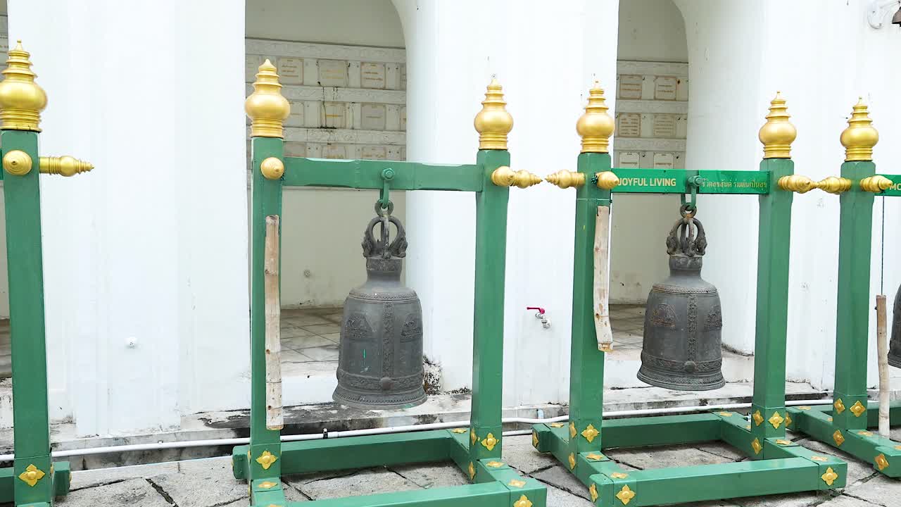 una vista serena de las campanas del templo en un patio de bangkok, que muestra la arquitectura tradicional y el ambiente cultural bajo la suave luz del día