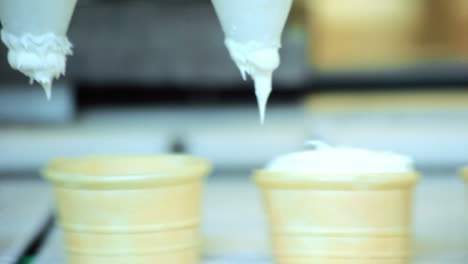 automated production line. closeup of ice cream pouring in waffle cup at factory