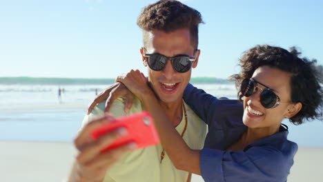 una pareja feliz tomando selfies en la playa.