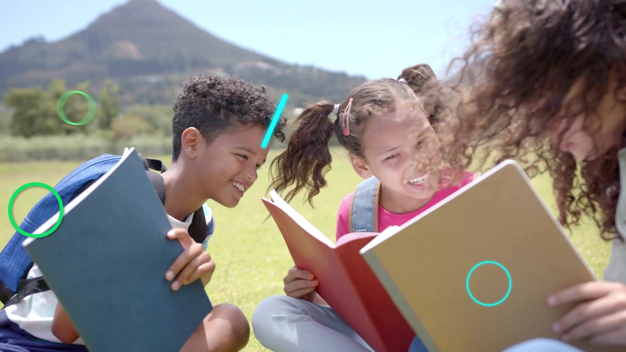 3 kids sitting on field, right girl sharing book, learning graphics obscuring then clearing pages