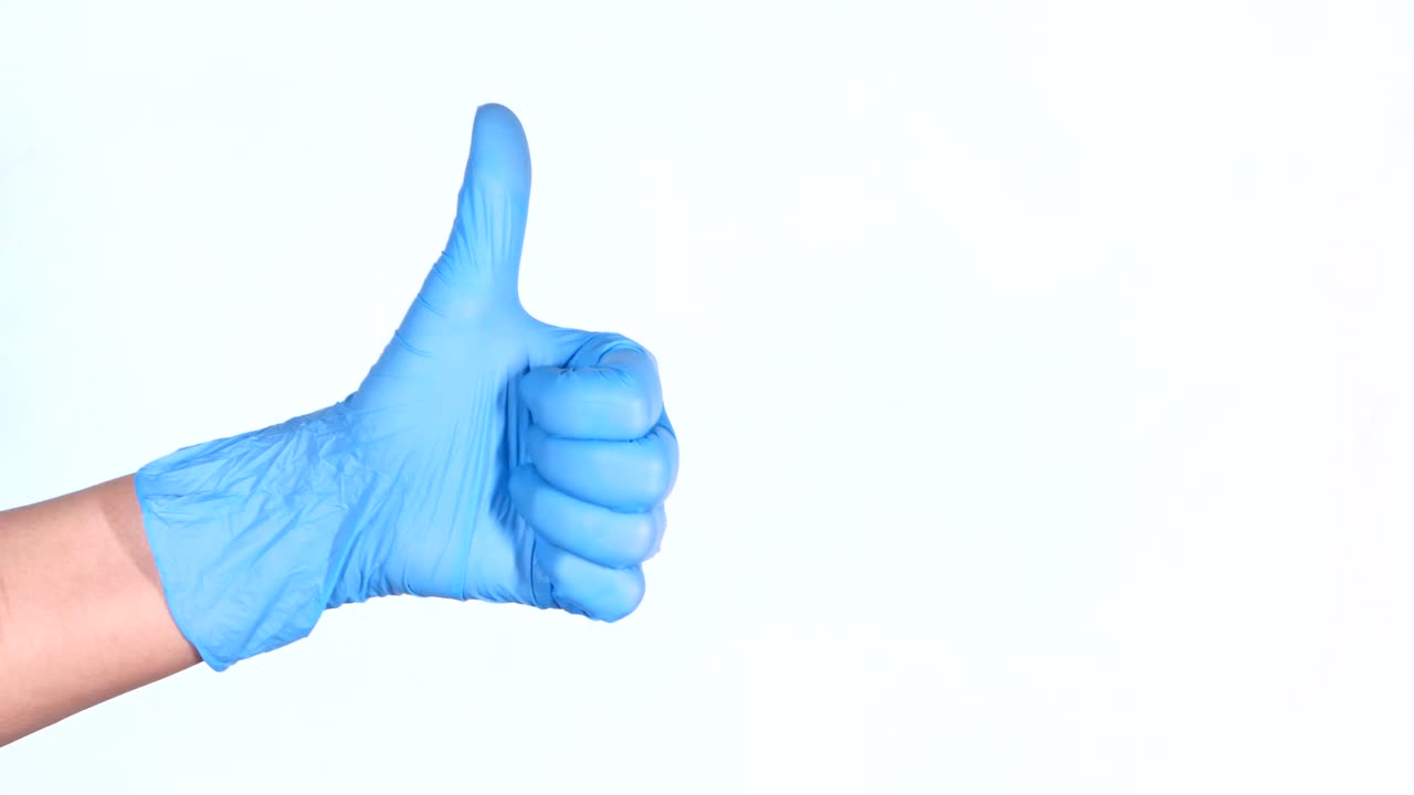 mano con guante médico azul dando un pulgar hacia arriba