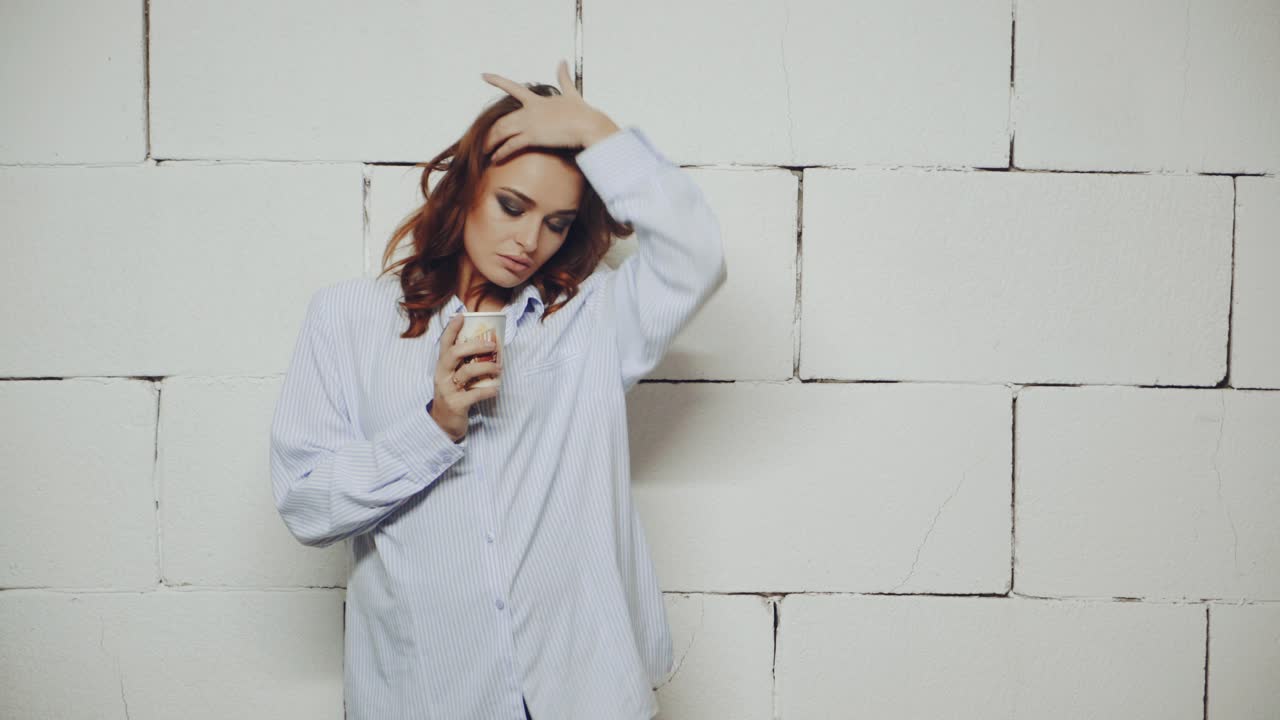 Woman drinking cup of coffee. Young stylish woman relaxing with cup of coffee in studio