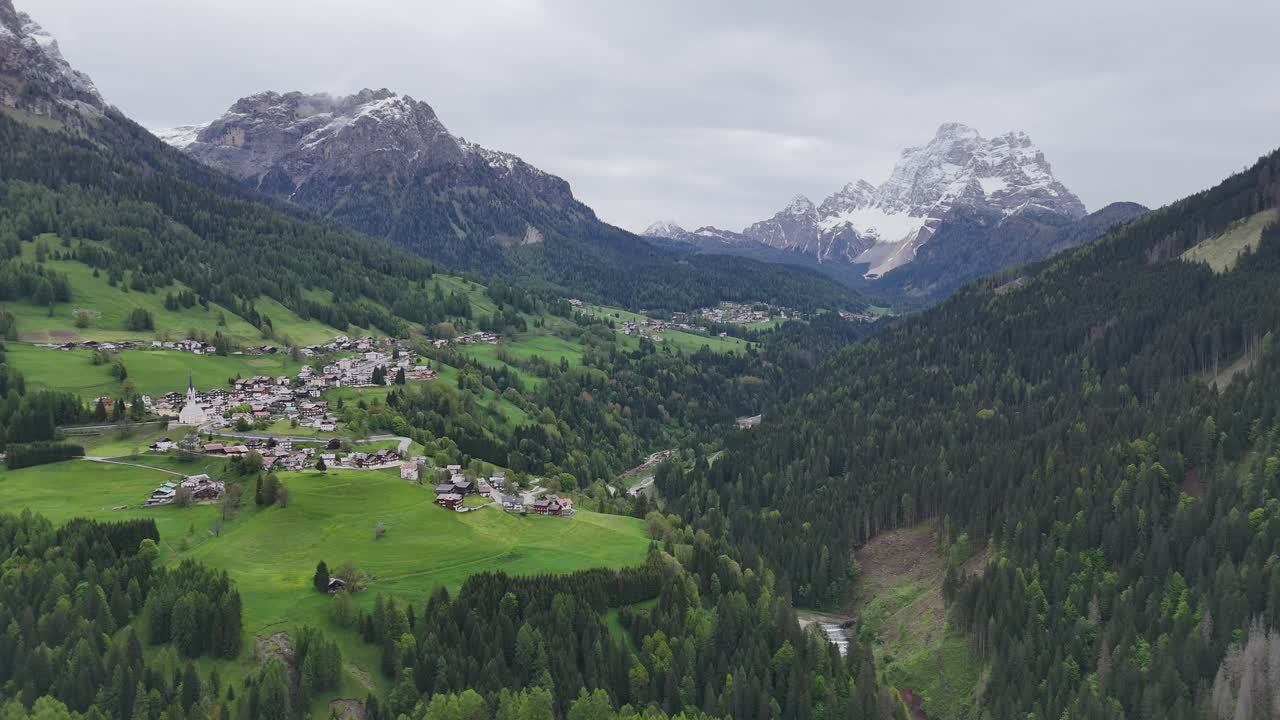 Selva di Cadore village surrounded by green hills and the dramatic Dolomite mountains.