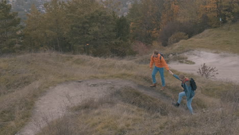 jóvenes excursionistas masculinos y femeninos con mochila subiendo la montaña