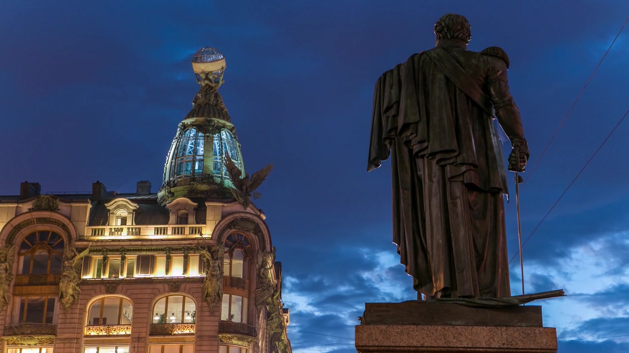 Il timelapse riprende la Casa Singer e il Monumento a Kutuzov a San Pietroburgo di notte durante il fenomeno delle notti bianche, con cieli nuvolosi che arricchiscono la scena.