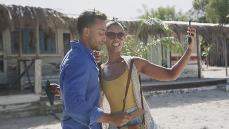 happy diverse couple arriving at beach hotel, taking selfie and man carrying woman, in slow motion