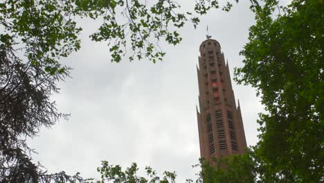 looking up on bell tower of church sainte-odile against dramatic sky in paris, france