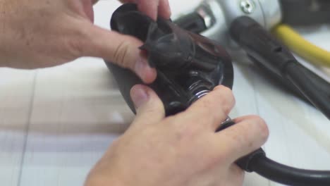 close-up of a woman’s hands checking a scuba diving regulator, inspecting the mouthpiece and hoses, breathing through the second stage to ensure no air leaks
