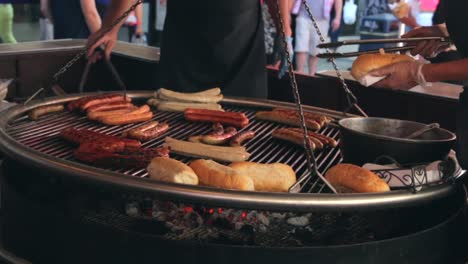 german sausages cooking on an open fire pit barbecue at a street food market.