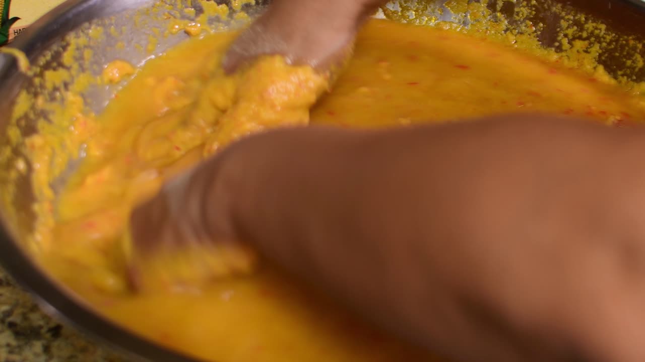 Woman’s hands kneading hallaca masa while pouring annatto oil, preparing traditional Venezuelan hallacas and showcasing authentic Latin American Christmas cooking