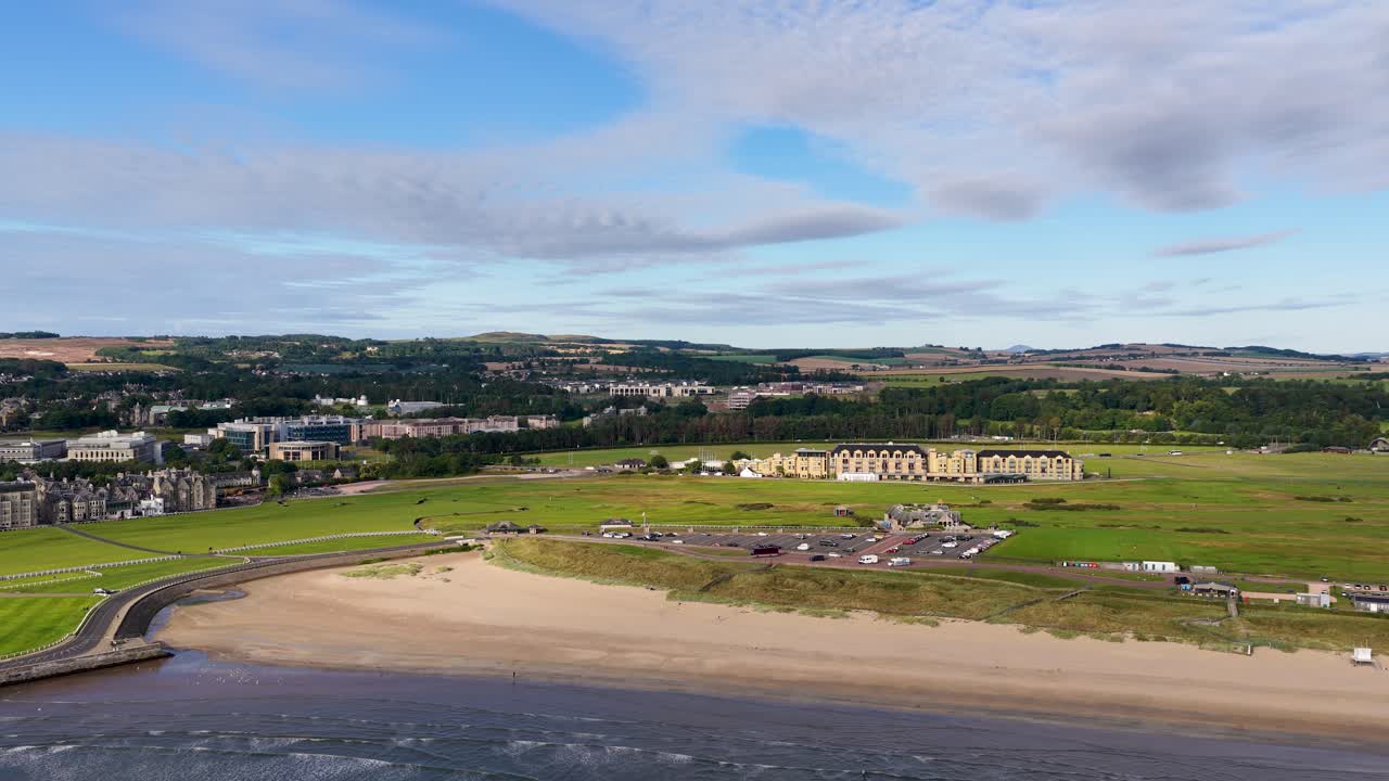 Drone glides over St Andrews coastline, historic golf course, sandy beach, and scenic landscape