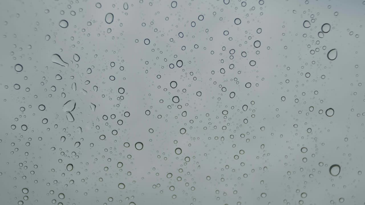 gotas de lluvia abstractas en el parabrisas del coche a cámara lenta