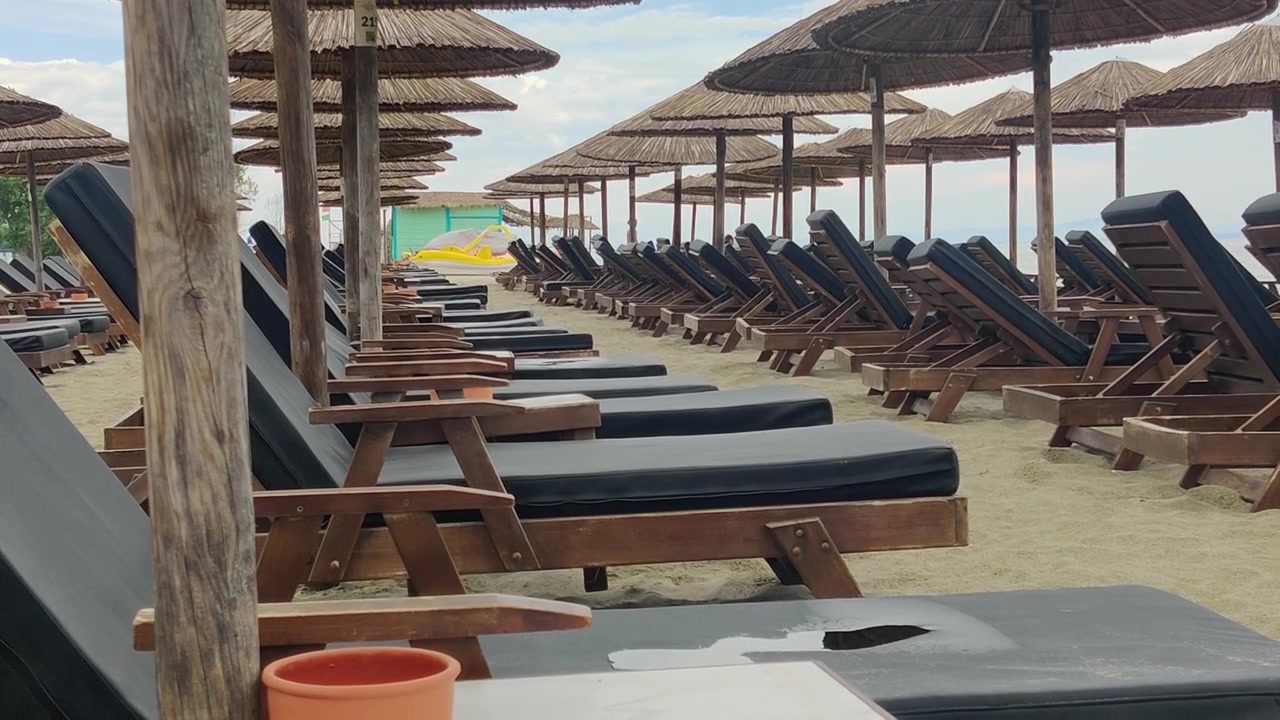Rows of empty beach loungers and parasols create orderly resort seating on sandy shore