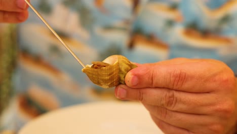 hands extracting clam meat with a toothpick