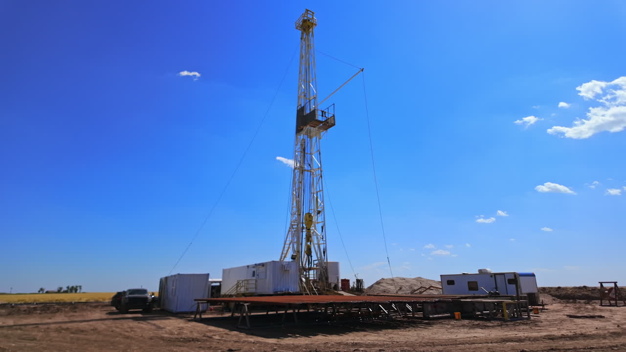 Approaching the little site for drilling natural resources in the desert. Borer at the derrick works producing oil. Low angle view.