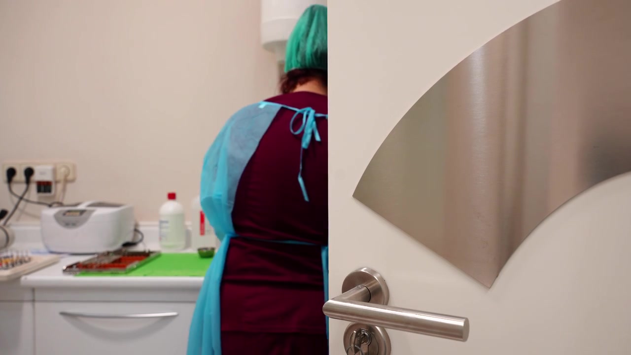 Dentista che organizza e pulisce i materiali nella sala di sterilizzazione dietro una porta semiaperta con chiave