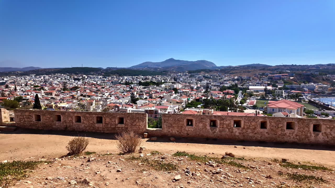 Pan shot capturing ancient architecture Venetian Fortezza Castle with cityscape of Rethimno in Greece.