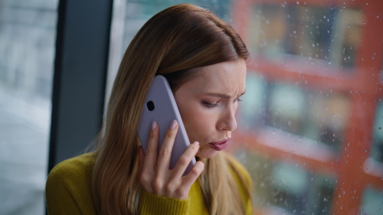Closeup joyful blonde calling cellphone standing by rainy window. Portrait woman