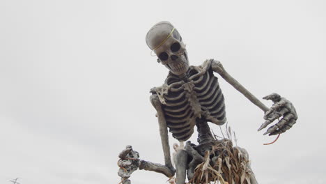 Skeleton-in-a-corn-skirt-against-a-cloudy-sky---Halloween-decor