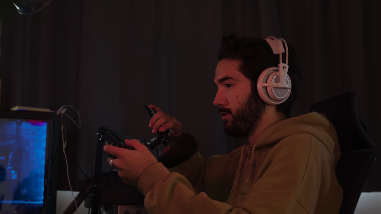 Male gaming with a game pad and talking into and moving a microphone while streaming
