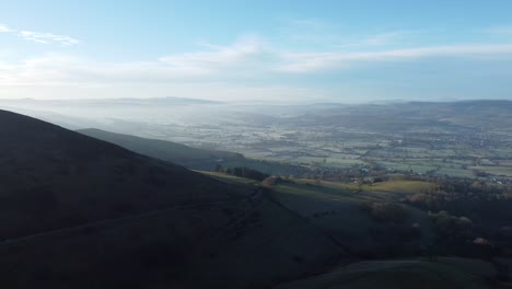 distant misty layers of panoramic rural mountain north wales valley countryside at sunrise aerial view slow pan right