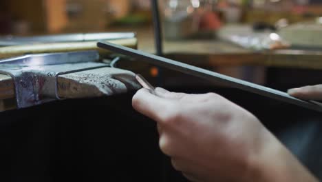 close up of hands of caucasian female jeweller using file making jewelry