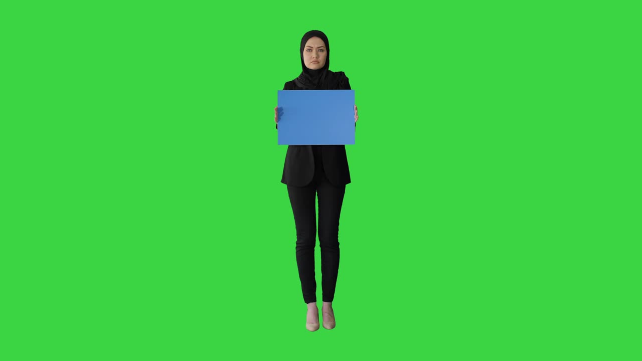 Muslim woman's protest Lady dressed in black and holding a blank card on a Green Screen, Chroma Key