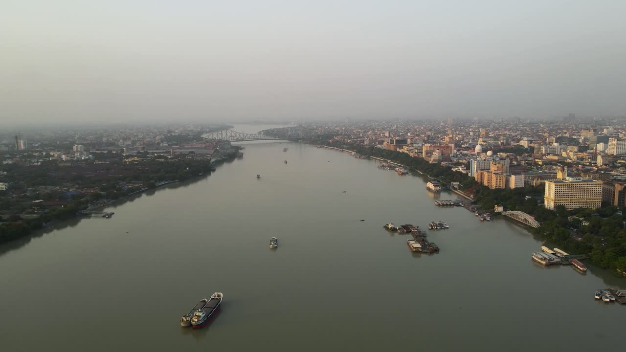 Stunning aerial view of the iconic Howrah Bridge over the serene waters of the Hooghly River in Kolkata.