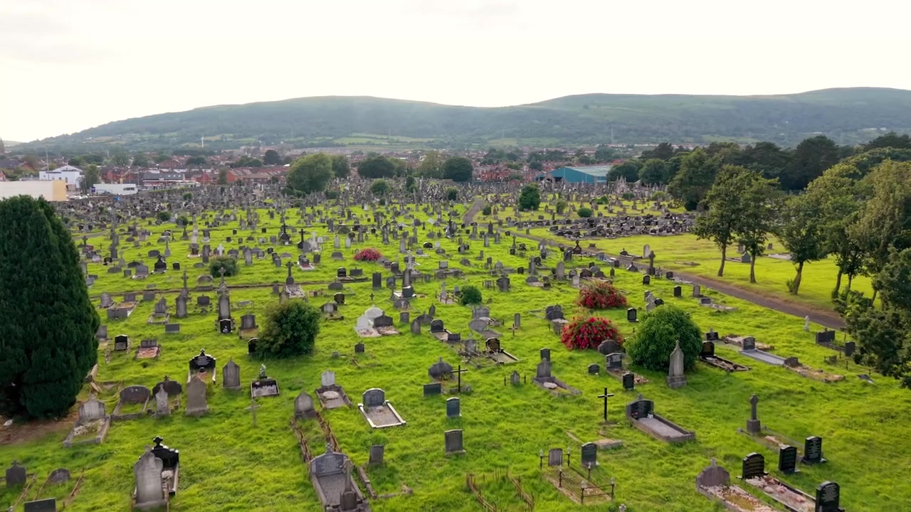Vídeo aéreo em 4K a 60FPS, em movimento lento, do Cemitério de Milltown e do Lote Republicano Irlandês na Falls Road em Belfast, Irlanda do Norte, Reino Unido. Produzido com cores Rec709 prontas para transmissão.