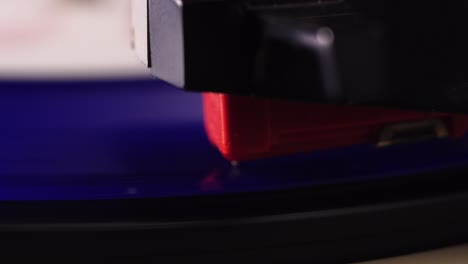 placing gramophone needle on spinning blue vinyl record, close up