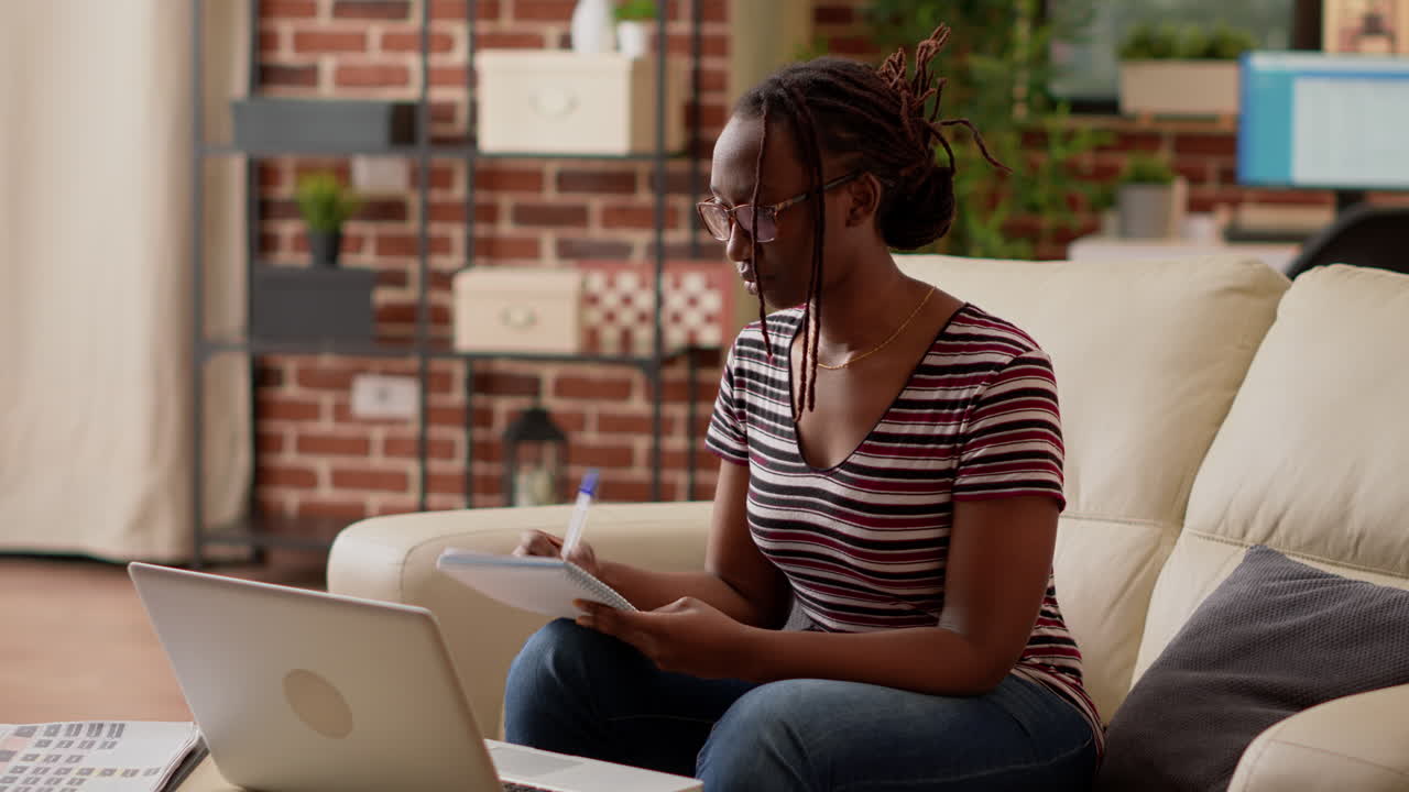 Woman working at home with laptop and notebook