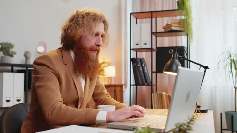 business man freelancer at home office table drinking morning coffee and working on laptop computer