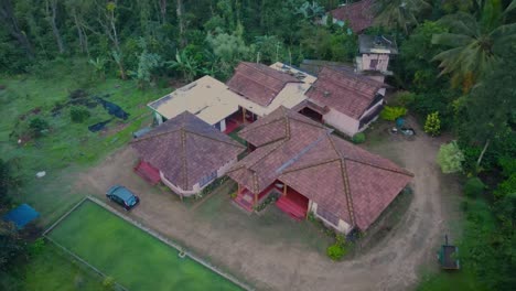 Ascending-aerial-shot-of-housing-complex-surrounded-by-tropical-nature-of-India