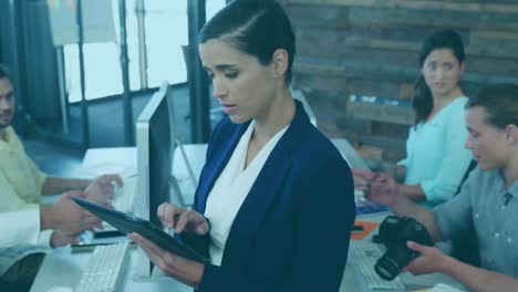 un ejecutivo de negocios usando una tableta digital mientras su colega trabaja en un escritorio en la oficina