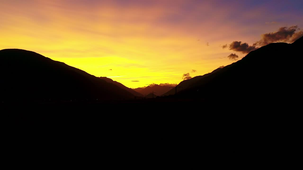 Yellow sky sunset of silhouetted mountains, warm golden tones highlight scene