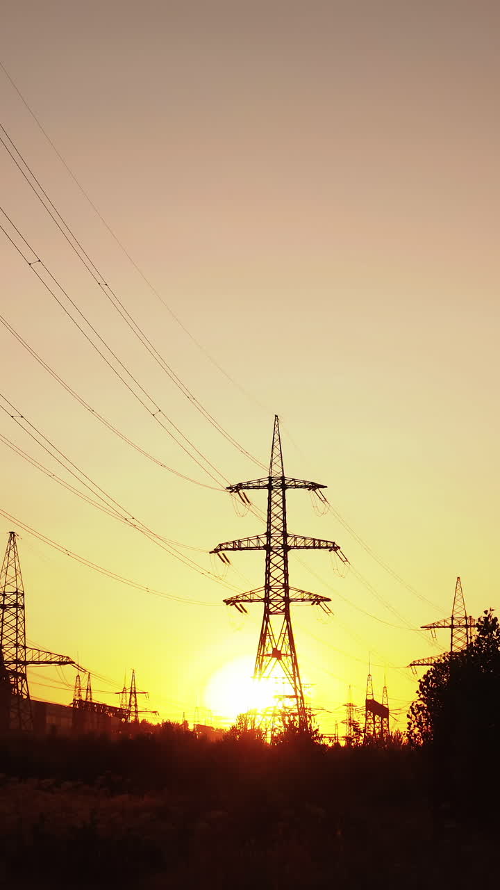 High voltage towers with sunset. Silhouette of columns and high voltage wires in the power supply station
