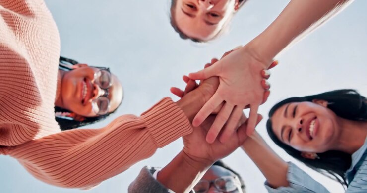 Grupo diversificado de amigos dando as mãos e comemorando juntos