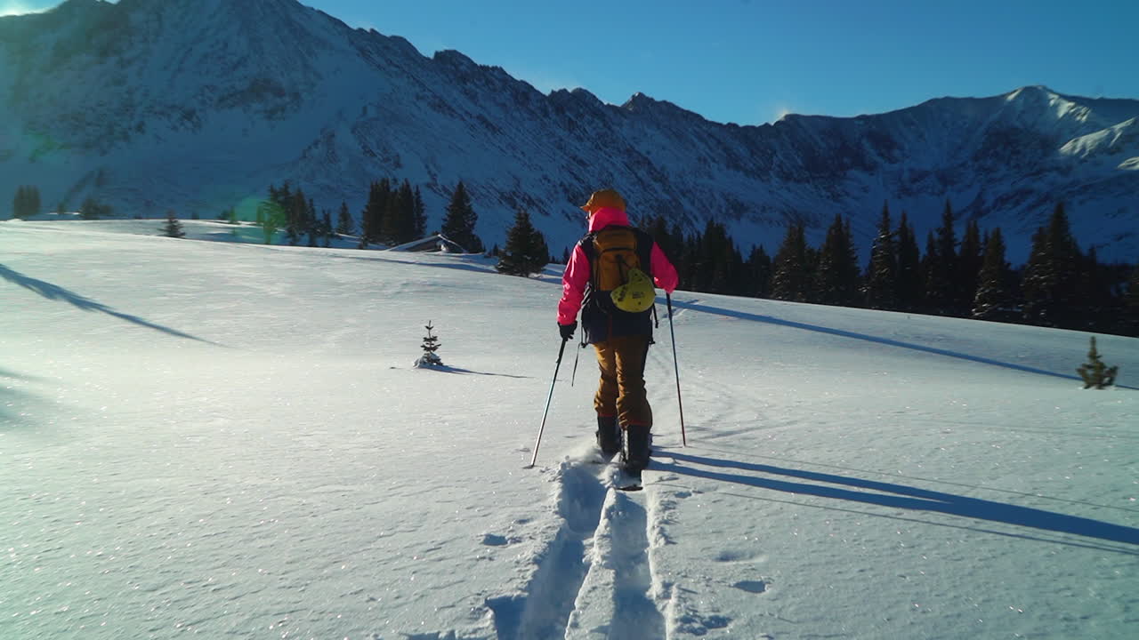 Cinematic stunning Colorado early morning Rocky Mountain backcountry skier split boarder up hill hiking fresh snow top peaks light treeline level Copper Breckenridge Aspen Vail follow zoom in out pan