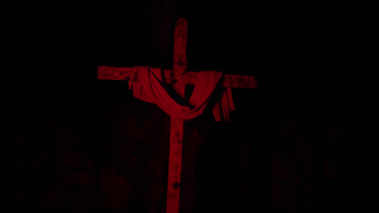 Red Illuminated Wooden Cross with Draped Cloth Outdoors
