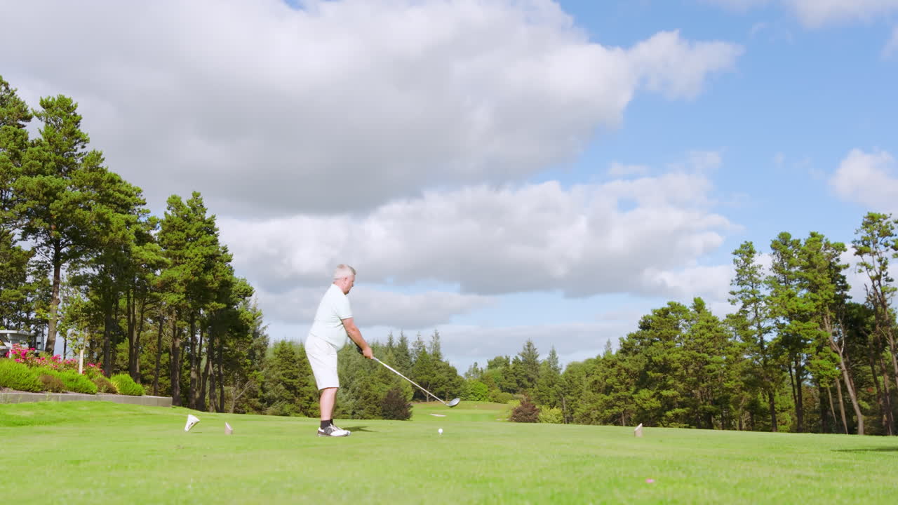 Male golf player playing golf and knocking golf ball out on golf course on cloudy day