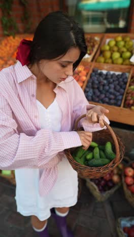 woman shopping for cucumbers at a farmer's market