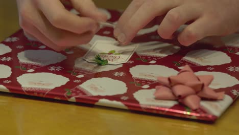 Nahaufnahme-Eines-Namensschilds,-Das-Auf-Ein-Verpacktes-Weihnachtsgeschenk-Geklebt-Wird