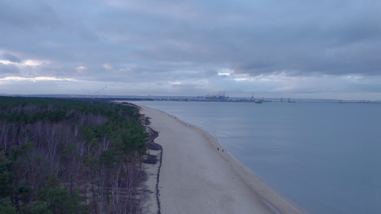 вид с воздуха на песчаный пляж в пасмурный день в гданьске и порт на заднем плане